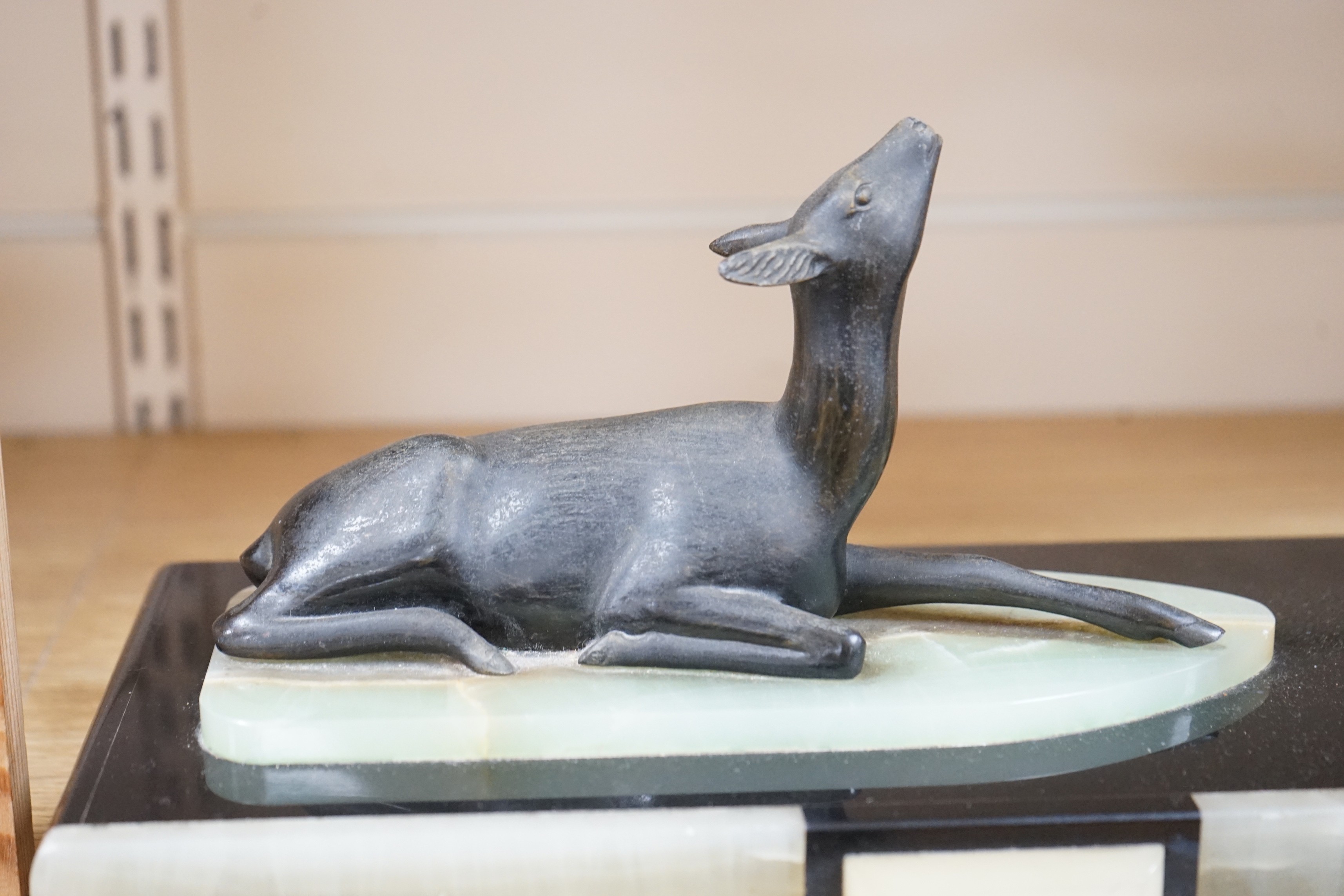 An Art Deco style bronzed metal female, with simulated ivory decoration, styled with fawn in recumbent stance. 56cm wide
